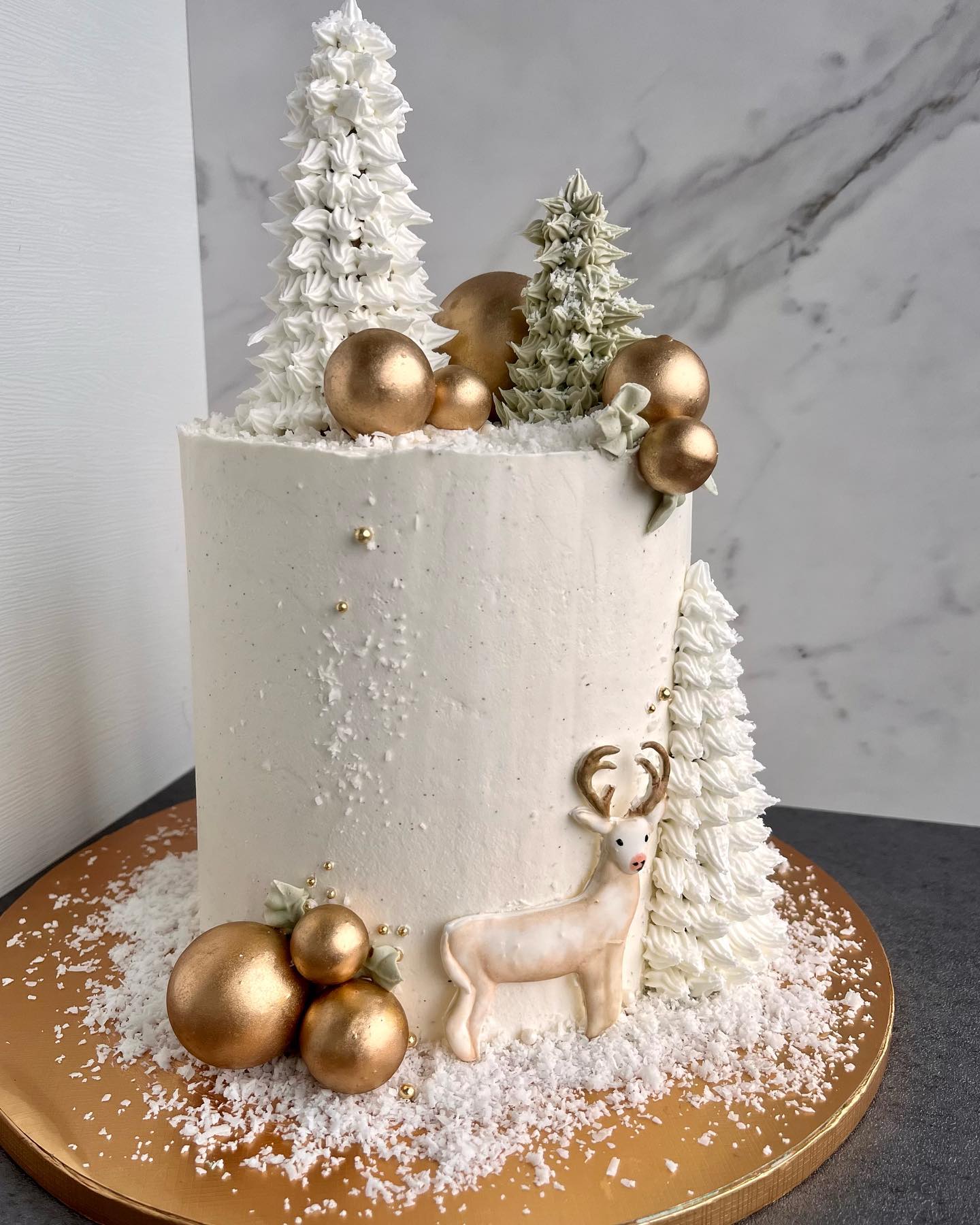 Winter forest cake with gold ornaments and a deer